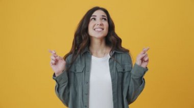 Gülümseyen bir kadın, sarı arka planda tek başına dururken bir dilek diliyor.