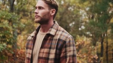 Çekici sarışın bir adam parkta yürüyor.