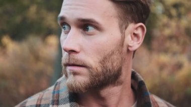 Sonbahar parkında yakışıklı bir adamın yakın çekim görüntüsü var.