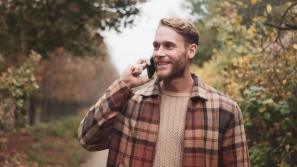 Усміхнений Блондинка Говорить Телефону Під Час Прогулянки Осінньому Парку — стокове відео