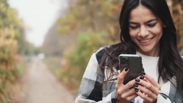 Eine Zufriedene Frau Benutzt Ihr Smartphone Beim Spaziergang Herbstpark — Stockvideo