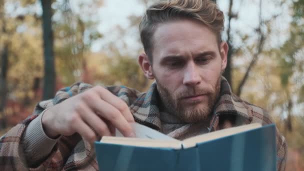 Орієнтований Чоловік Читає Книгу Сидячи Осінньому Парку — стокове відео