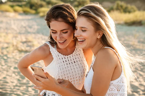 Twee Jonge Blanke Vrolijke Vrouwen Glimlachend Kijkend Naar Mobiele Telefoon — Stockfoto