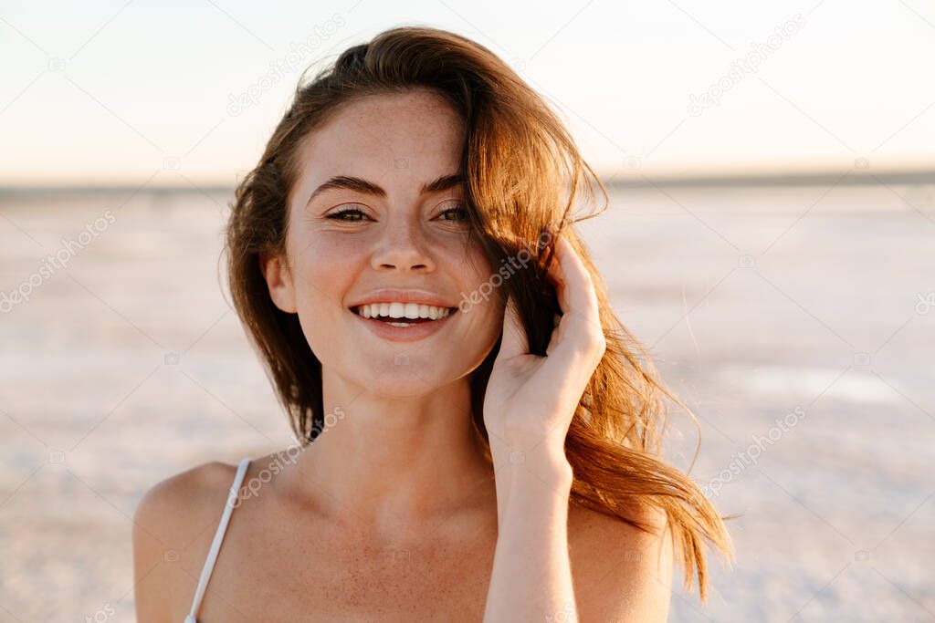 Image of a happy young pretty girl walking outdoors at the beach