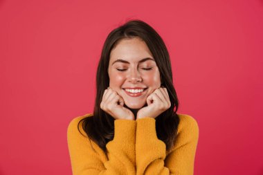 Pembe arka planda izole edilmiş kameraya poz veren ve gülümseyen mutlu güzel bir kız görüntüsü