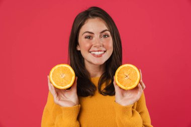 Pembe arka planda turuncuyla poz veren neşeli beyaz kız.