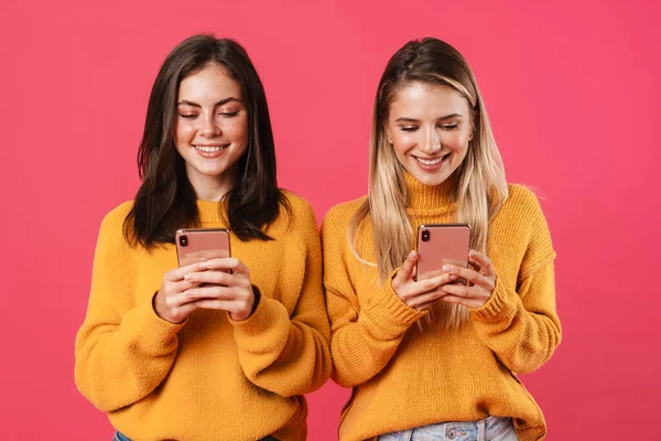 ピンクの背景に隔離されたスマートフォンを使用している間に笑顔の素敵な女性のイメージ — ストック写真