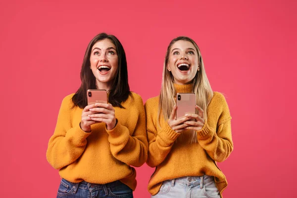 ピンクの背景に隔離されたスマートフォンを使用しながら笑顔の嬉しい素敵な女性のイメージ — ストック写真