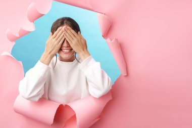 Beyaz tenli güzel bir kadın gülümsüyor ve pembe arka plandan izole edilmiş gözlerini kapatıyor.