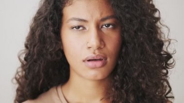 Ciddi bir Afrikalı Amerikalı kadının yakın plan görüntüsü, bej arka planda tek başına duran negatif bir şekilde başını sallıyor.