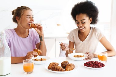 Güzel, neşeli, çok kültürlü kızlar birlikte kahvaltı ederken gülüyorlar.
