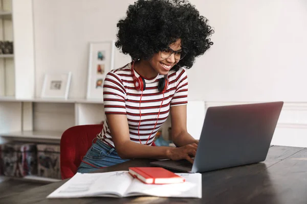 Sonriendo Chica Estudiante Afroamericana Haciendo Tarea Con Ordenador Portátil Mientras —  Fotos de Stock