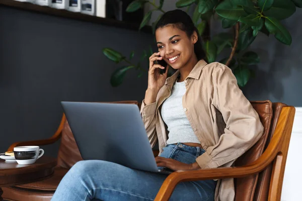 Vreugdevolle Afrikaanse Amerikaanse Vrouw Praten Mobiele Telefoon Tijdens Het Werken — Stockfoto