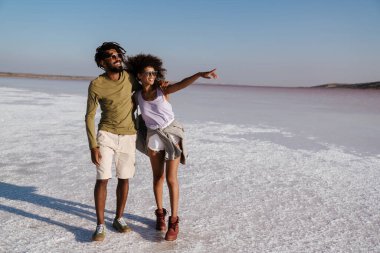 Sevgi dolu genç Afrikalı çift deniz kıyısında yürüyor.