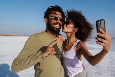 Mutlu Afro-Amerikan çifti, Salt Valley 'de öpüşüp selfie çekerken görüntüsü.