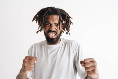 Beyaz arka planda izole edilmiş yumruklarla poz veren kızgın Afrikalı Amerikalı adamın fotoğrafı.