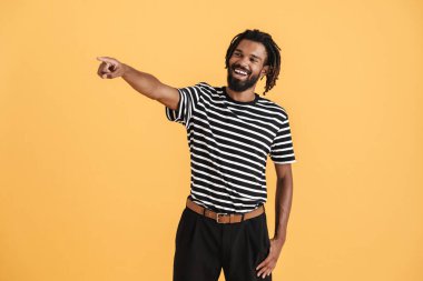 Gülen Afrikalı Amerikalı adamın sarı arka planda izole edilmiş bir şekilde işaret ettiği fotoğraf.