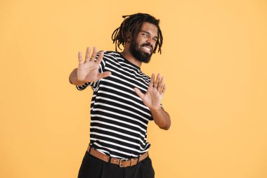 Kırgın Afrikalı Amerikalı adamın sarı arka planda izole edilmiş dur hareketi gösteren fotoğrafı.