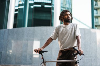 Yakışıklı Afro-Amerikan adam. Bisikletle şehir caddesinde poz veriyor.