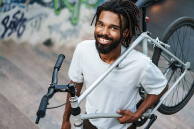 Mutlu Afrikalı Amerikalı adam bisiklet sürerken gülümsüyor.