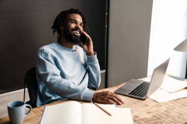 Masada çalışan kendinden emin Afrikalı serbest çalışan genç bir adam.