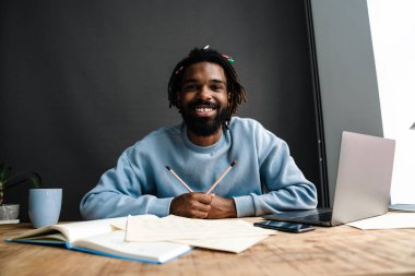 Masada çalışan kendinden emin Afrikalı serbest çalışan genç bir adam.