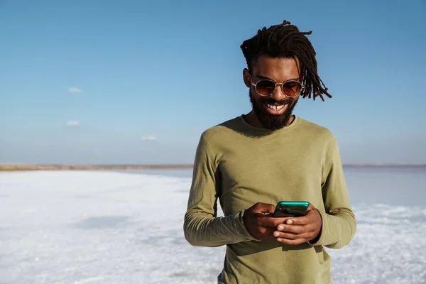 幸せなアフリカ系アメリカ人の男性の笑顔と塩の谷で携帯電話を使用するイメージ — ストック写真