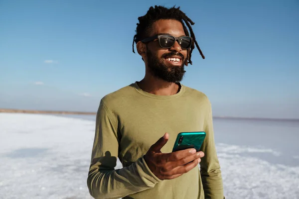Obrázek Šťastného Afrického Američana Úsměvem Pomocí Mobilního Telefonu Solném Údolí — Stock fotografie