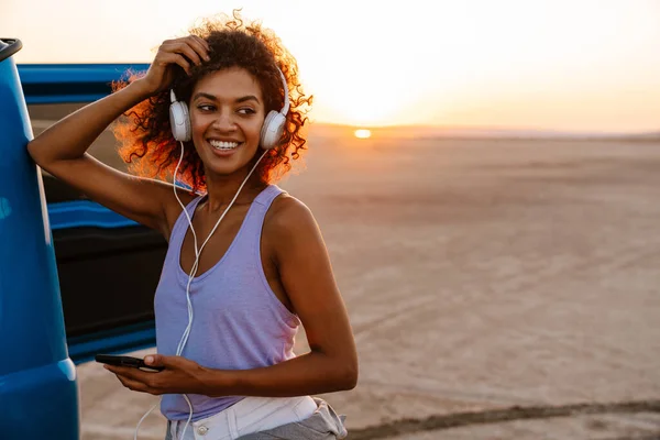 Obraz Szczęśliwej Afroamerykanki Korzystającej Słuchawek Telefonu Komórkowego Podczas Podróży Samochodem — Zdjęcie stockowe