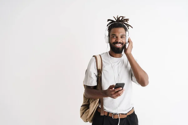 白い背景の上に隔離された携帯電話とヘッドフォンを使用して楽しいアフリカ系アメリカ人の男の写真 — ストック写真