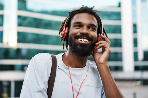 陽気なアフリカ系アメリカ人の男リスニング音楽とともにヘッドフォンで街の通り — ストック写真