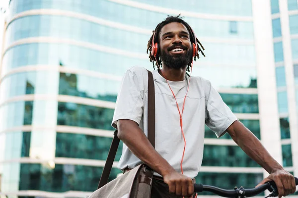 Wesoły Afrykański Amerykanin Słuchawkach Pozujący Rowerem Ulicy Miejskiej — Zdjęcie stockowe