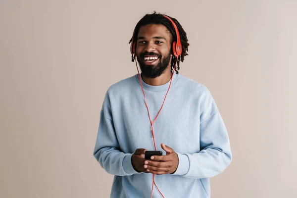 戴耳机的快乐的非洲裔美国人 用的是白色背景的手机 — 图库照片