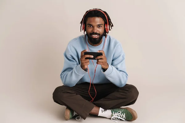 Pria Afrika Yang Ceria Headphone Menggunakan Ponsel Saat Duduk Lantai — Stok Foto