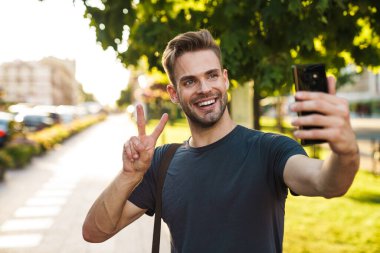 Sokakta selfie çeken heyecanlı genç adam.