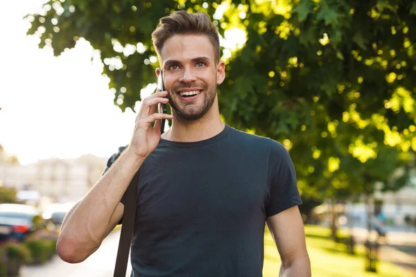 Sonriente Joven Atractivo Hablando Por Teléfono Móvil Mientras Camina Por —  Fotos de Stock