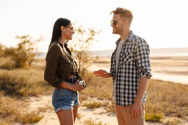 Güzel mutlu çift yazın doğada dolaşırken konuşuyor ve gülümsüyor.