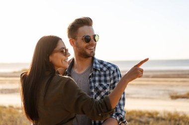 Güzel mutlu çift yaz aylarında doğada dolaşırken kucaklaşıp parmakla işaret ediyorlar.