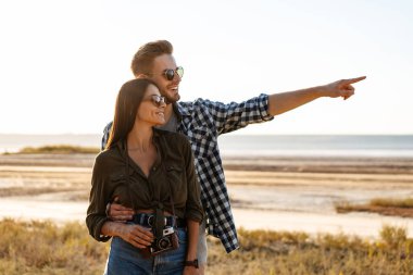 Güzel mutlu çift yaz aylarında doğada dolaşırken kucaklaşıp parmakla işaret ediyorlar.