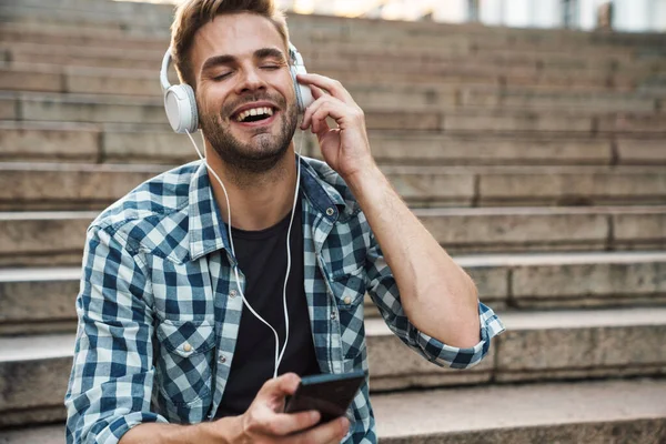 Homem Atraente Fones Ouvido Segurando Telefone Celular Enquanto Sentado Passos — Fotografia de Stock