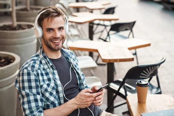 Jovem Sorridente Usando Fones Ouvido Sentado Mesa Café Livre Usando — Fotografia de Stock