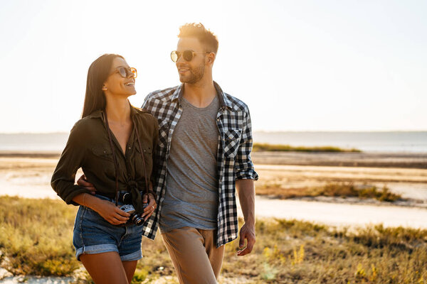 Прекрасная счастливая пара, обнимающая и улыбающаяся во время прогулок по природе летом