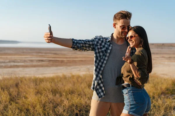 Ζευγάρι Gesturing Σημάδι Ειρήνης Και Λήψη Selfie Στο Κινητό Ενώ — Φωτογραφία Αρχείου