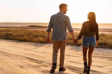 Güzel mutlu çift yazın doğada dolaşırken el ele tutuşup gülümsüyor.