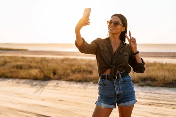 Όμορφη Χαρούμενη Κοπέλα Λήψη Selfie Στο Κινητό Ενώ Δείχνει Την — Φωτογραφία Αρχείου