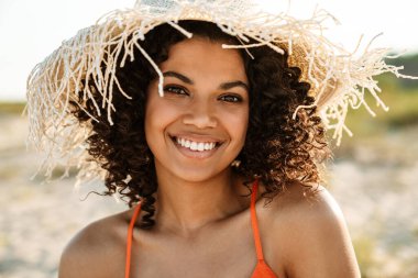 Sahilde poz veren mutlu, pozitif, genç bir Afrikalı kadın.