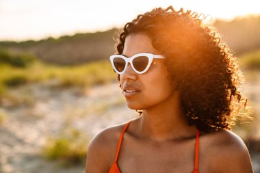 Sahilde güneş gözlüğü takan Afro-Amerikan bir kadının fotoğrafını çek.