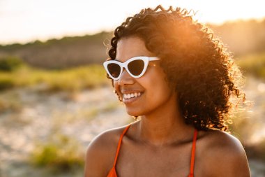 Sahilde güneş gözlüğü takan Afro-Amerikan bir kadının fotoğrafını çek.