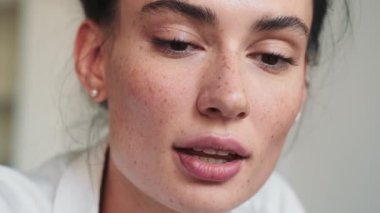 Memnuniyet duyan bir kadının yakın plan görüntüsü evde oturan dizüstü bilgisayarını kullanıyor.