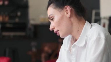 Güzel bir kadın kafenin içinde dizüstü bilgisayarını kullanıyor.